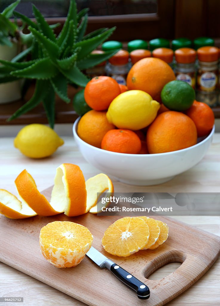 Orange being sliced on chopping baord in kitchen