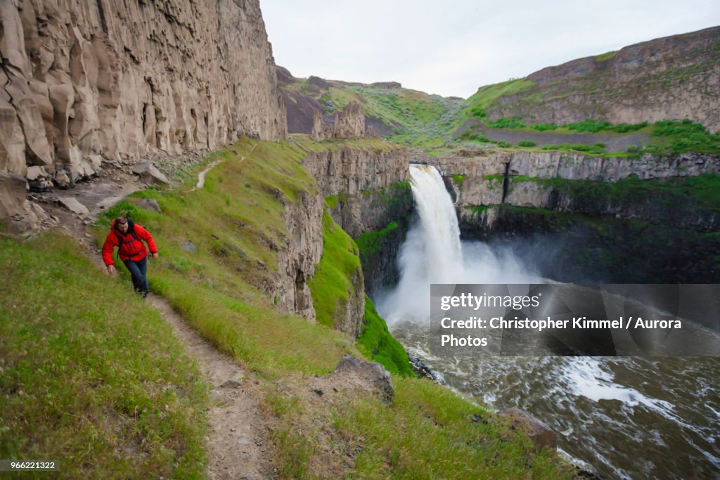 Backpacker hiking along cliff at Palouse Falls State Park, Washington State, USA