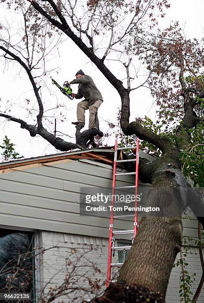 Worker Tony Montealbo uses a chainsaw to remove a large tree that crashed through a Dallas home February 12, 2010 in Dallas, Texas. More than 10...