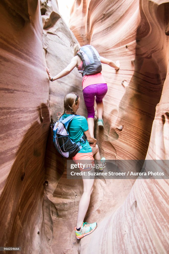 Two women canyoneering through narrow Zebra Canyon, Grand Staircase-Escalante National Monument, Utah, USA