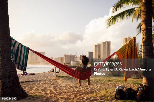 young woman sitting in hammock at beach, honolulu, hawaii islands, usa - honolulu foto e immagini stock