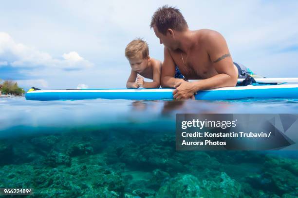 father and son with surf board in ocean,bali,indonesia - kids fun indonesia stock-fotos und bilder