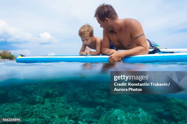father and son with surf board in ocean,bali,indonesia - kids fun indonesia stock pictures, royalty-free photos & images