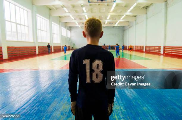 rear view of player standing at indoor soccer court - fußballtrikot rücken stock-fotos und bilder