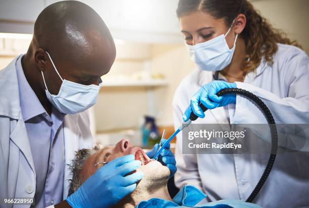 odontólogo y asistente dental trabajando en dientes del paciente - suction tube fotografías e imágenes de stock