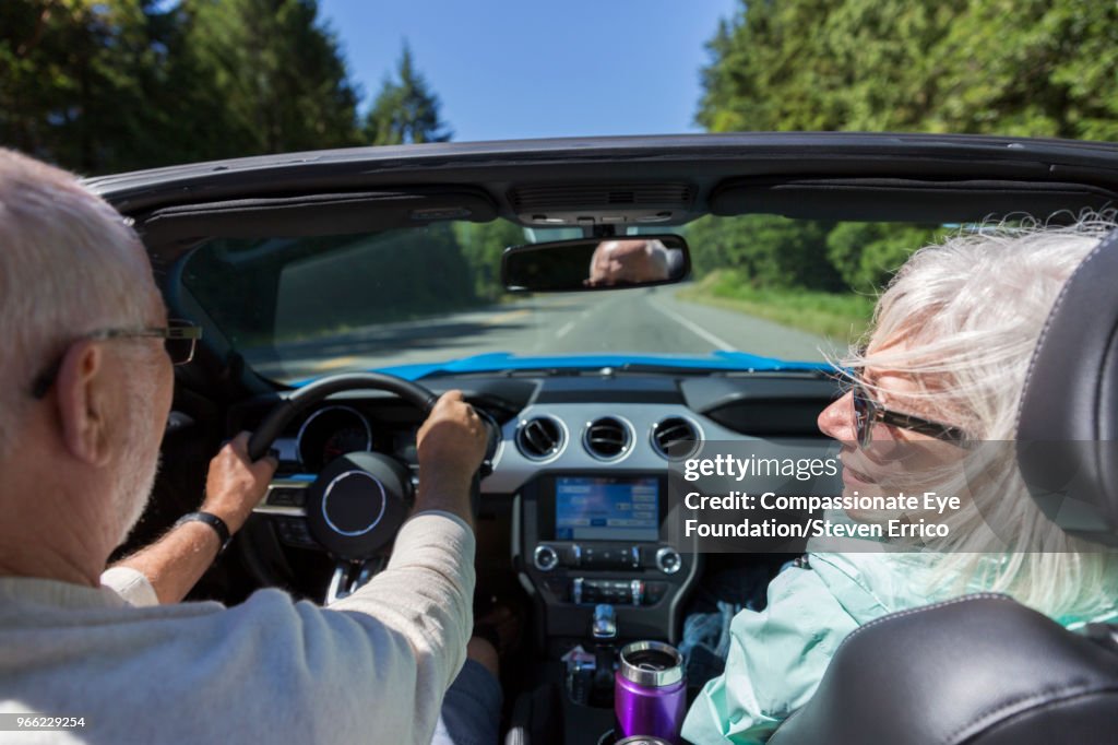 Senior couple driving in convertible