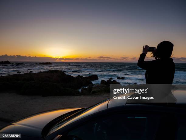 silhouette teenage girl photographing while standing in sun roof - isolated car people stock pictures, royalty-free photos & images