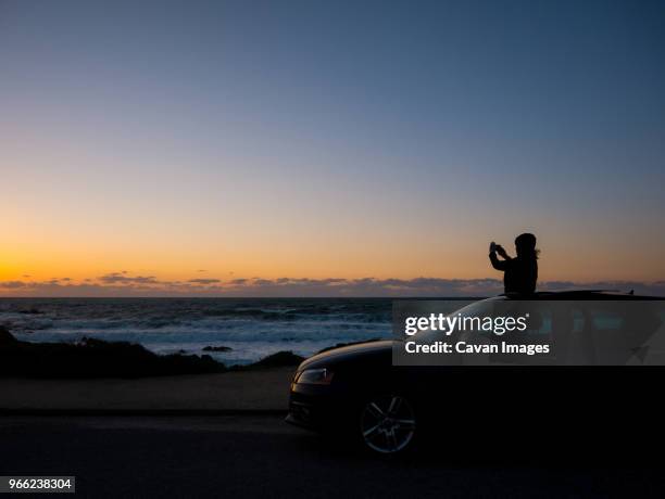 silhouette teenage girl photographing while standing in sun roof during sunset - soltak bildbanksfoton och bilder