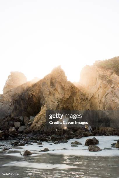 mid distance view of teenage girl standing by rock formations at beach against clear sky - mendocino stock-fotos und bilder