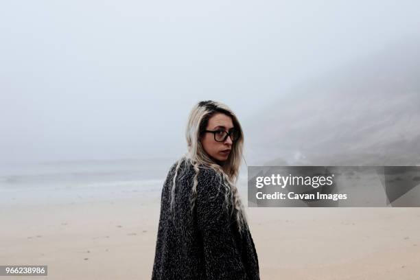 portrait of woman standing at beach during foggy weather - maine winter stock pictures, royalty-free photos & images