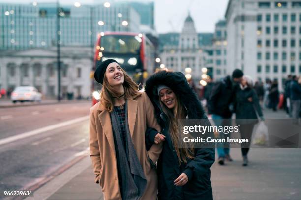 smiling friends walking on road in city - london winter stock pictures, royalty-free photos & images