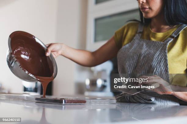 midsection of woman pouring chocolate sauce in mold - liquid chocolate stock pictures, royalty-free photos & images