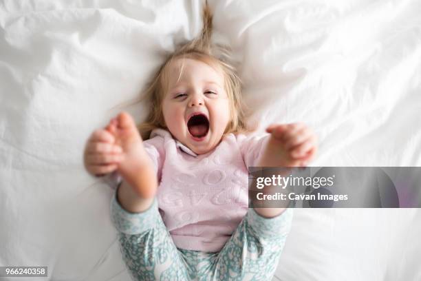 portrait of happy baby girl lying on bed at home - weibliches baby stock-fotos und bilder