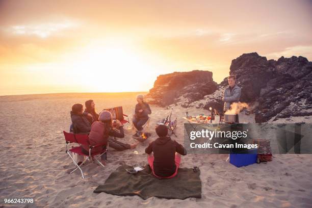 friends camping at beach during sunset - beach picnic stock pictures, royalty-free photos & images