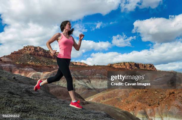 woman jogging on field against cloudy sky - paria canyon foto e immagini stock