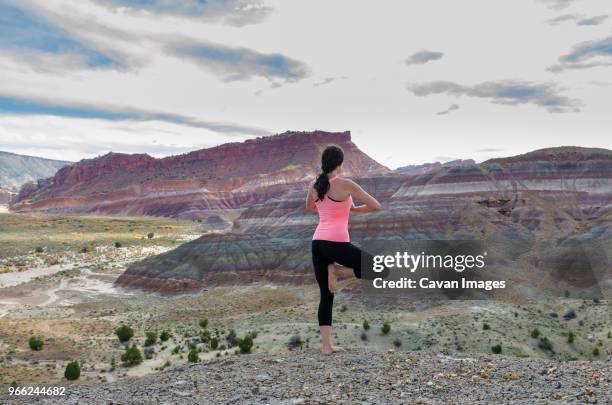 rear view of woman standing in tree pose on rock formation - paria canyon foto e immagini stock