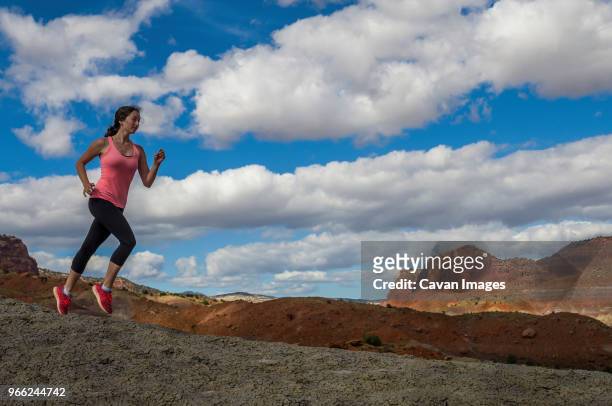 athlete running on rock formations against cloudy sky - paria canyon stock pictures, royalty-free photos & images