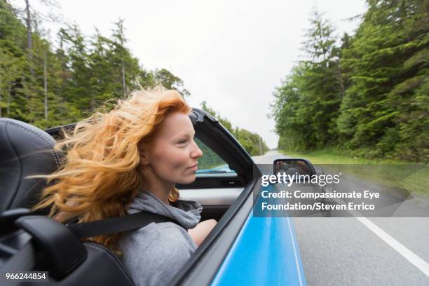 young woman driving in convertible - tofino foto e immagini stock