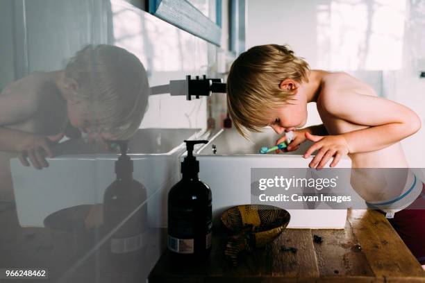 side view of shirtless boy spitting while brushing teeth - spitting stock pictures, royalty-free photos & images