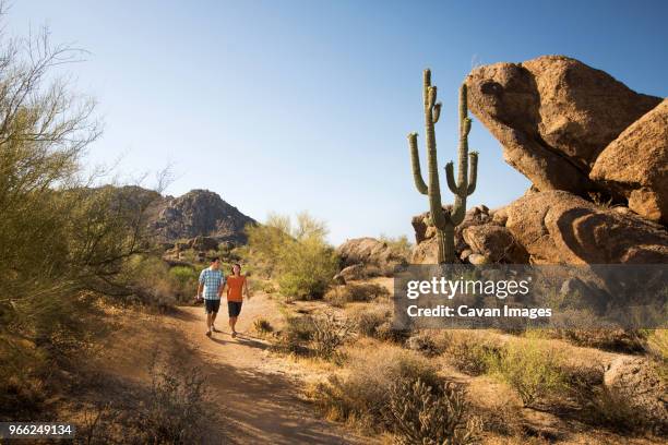 couple walking on dirt road in desert against clear sky - scottsdale arizona stockfoto's en -beelden