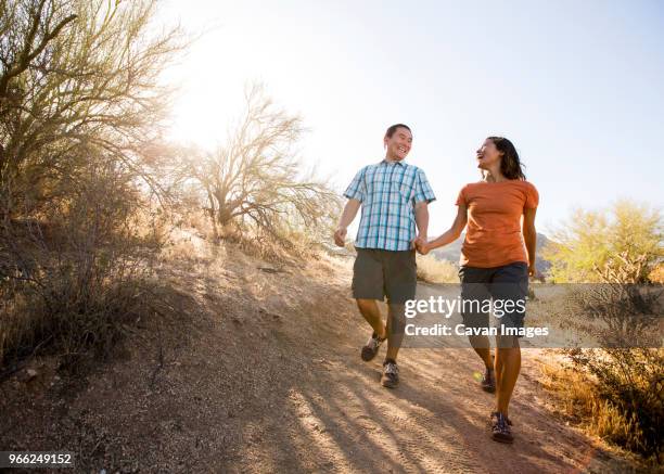 happy couple walking on dirt road against clear sky - scottsdale arizona stock-fotos und bilder