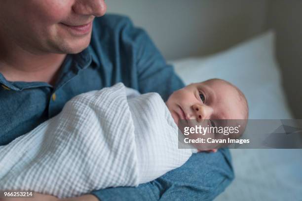 portrait of cute newborn baby boy being carried by father at home - baby blanket stock pictures, royalty-free photos & images