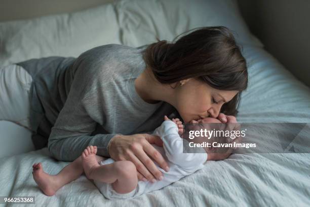 high angle view of mother kissing crying newborn baby boy on forehead in bed - moms crying in bed stock pictures, royalty-free photos & images