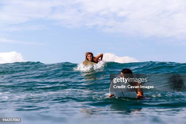 happy friends surfing on sea against sky - indonesia surfing imagens e fotografias de stock