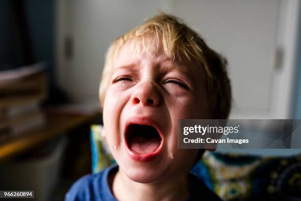 close-up of boy crying at home - child crying stock-fotos und bilder