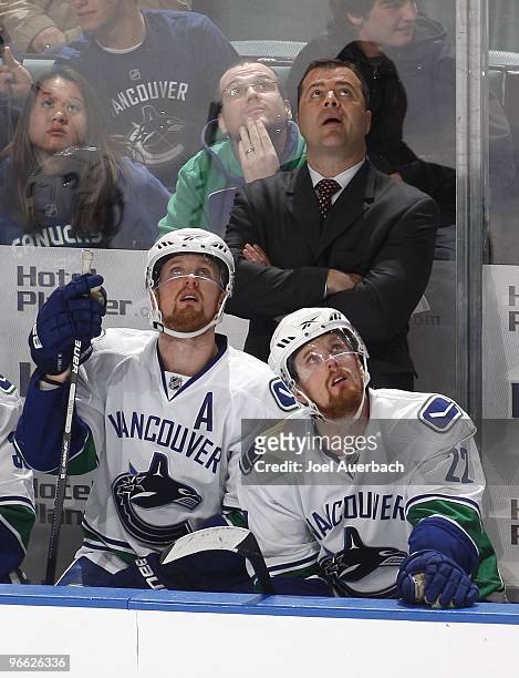 Head coach Alain Vigneault, Henrik Sedin and Daniel Sedin of the Vancouver Canucks watch a replay during a time out late in the third period of the...