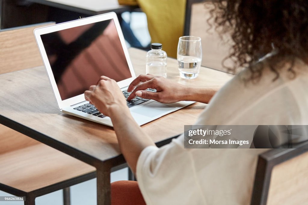 Businesswoman using laptop at table in cafe