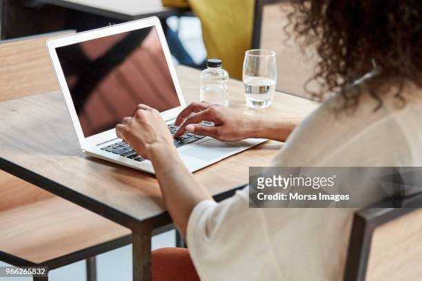 businesswoman using laptop at table in cafe - over the shoulder view 個照片及圖片檔