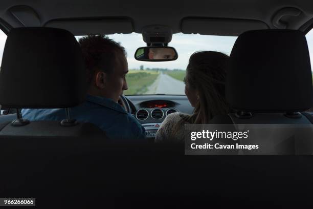 rear view of couple looking at each other in car during vacation - repose tête photos et images de collection