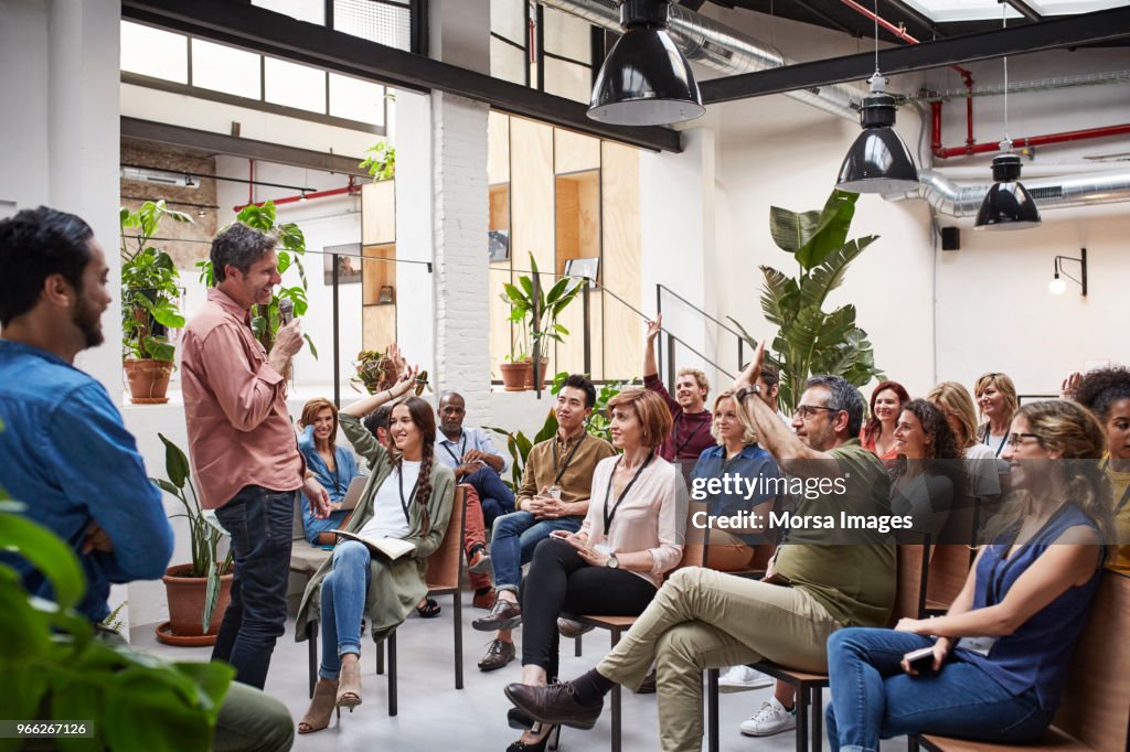 Business people with raised arms during seminar
