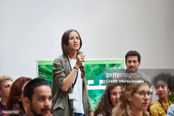 businesswoman talking into microphone in seminar - discorso foto e immagini stock