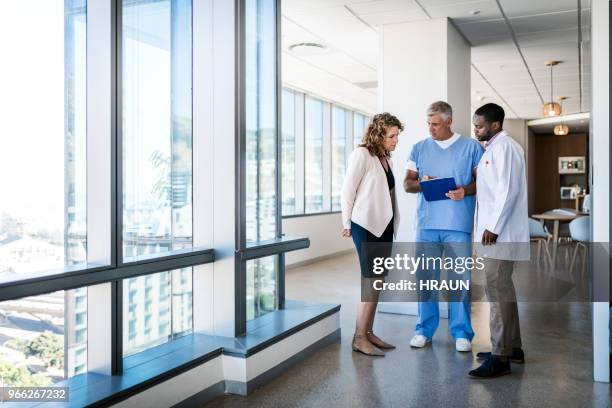 doctors discussing over clipboard in hospital - doctor chart stock pictures, royalty-free photos & images