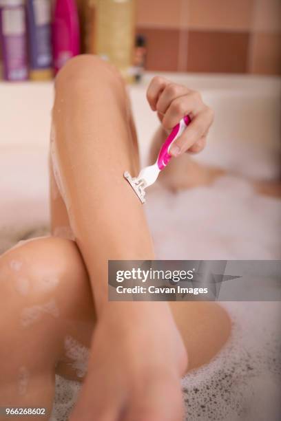 cropped image of teenage girl shaving legs while lying in bathtub - girl shaving legs stock pictures, royalty-free photos & images