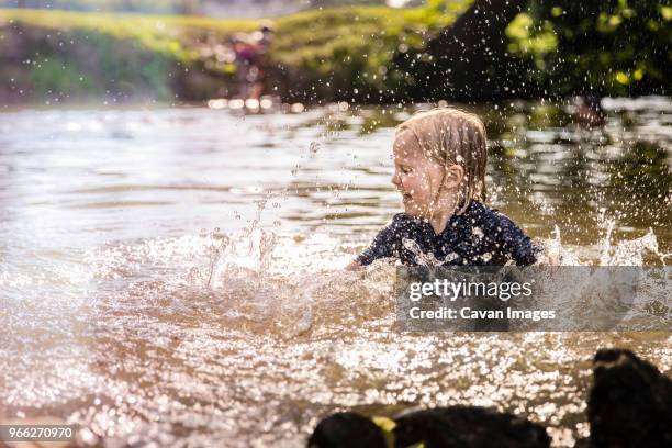 carefree girl splashing water while playing in lake - westminster maryland stock pictures, royalty-free photos & images