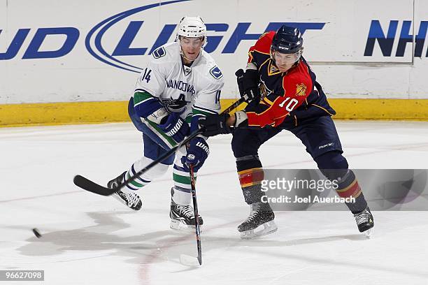 David Booth of the Florida Panthers is able to get a shot on goal off while being defended by Alexandre Burrows of the Vancouver Canucks on February...