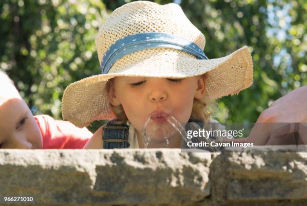 close-up of boy looking at sister drinking water from fountain - hands fountain water stock-fotos und bilder