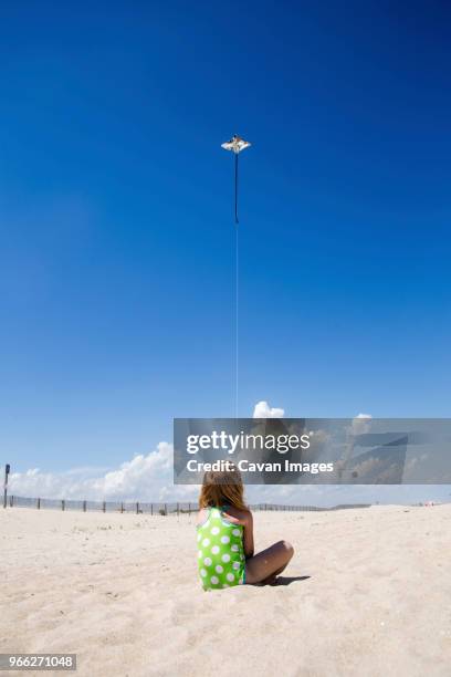 rear view of girl flying kite while sitting at beach during sunny day - westminster maryland fotografías e imágenes de stock