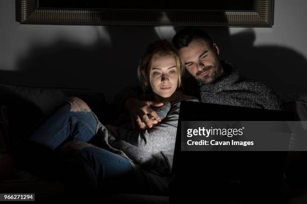 couple using laptop computer in darkroom at home - dark room stock-fotos und bilder