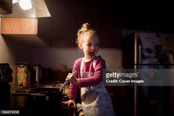 happy girl looking away while preparing food in kitchen at home - refrigerator front stock pictures, royalty-free photos & images