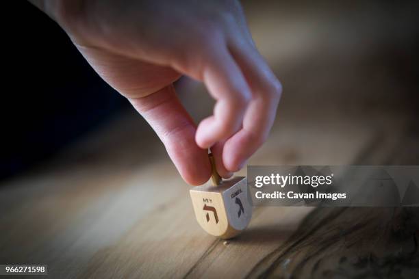 cropped hand of man spinning dreidel on table - dreidel stock pictures, royalty-free photos & images