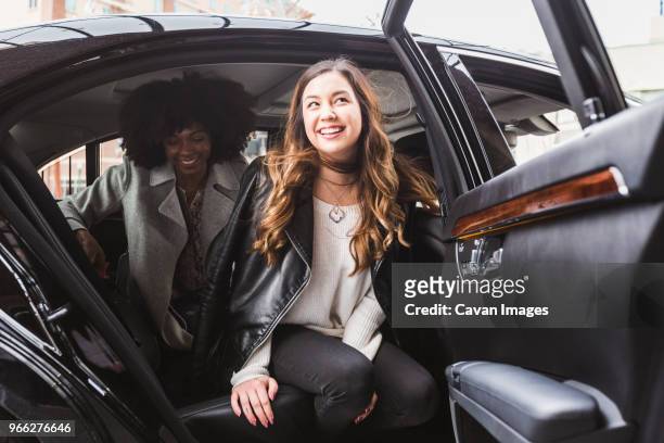cheerful businesswomen disembarking from car - auto aussteigen stock-fotos und bilder