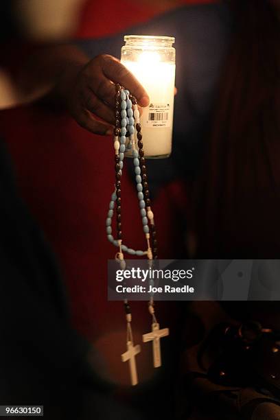 Person of Haitian descent holds a candle and rosary during a prayer vigil at the Notre Dame d'Haiti Catholic church as they mark the one month...