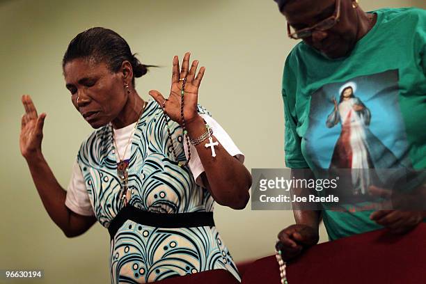 Lavanie Delva and Assefie Prospere pray together during a vigil at the Notre Dame d'Haiti Catholic church as they mark the one month anniversary of...