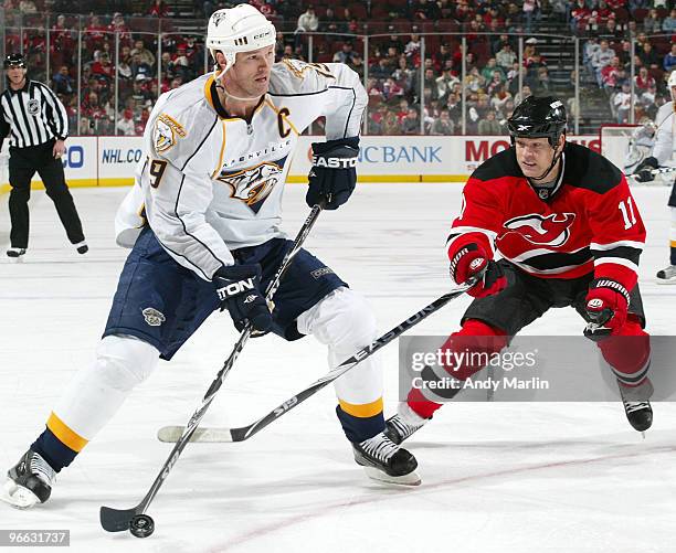 Jason Arnott of the Nashville Predators controls the puck while being defended by Dean McAmmond of the New Jersey Devils during the game at the...