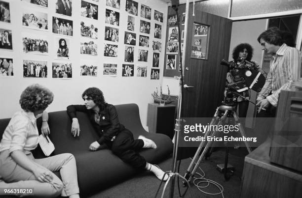 Eric Hall, Head of Promotions at EMI Records, in front of a film crew in his office with Marc Bolan at back at Manchester Square, London, 1977.