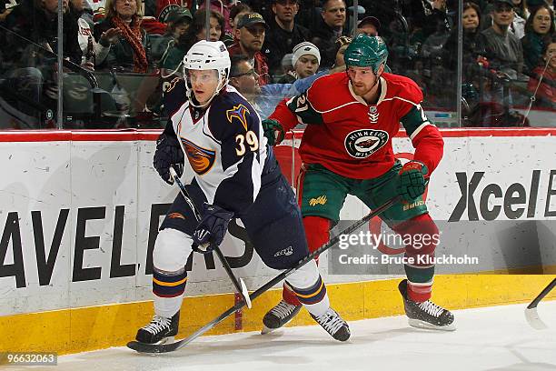 Kyle Brodziak of the Minnesota Wild and Tobias Enstrom of the Atlanta Thrashers skate to the puck during the game at the Xcel Energy Center on...